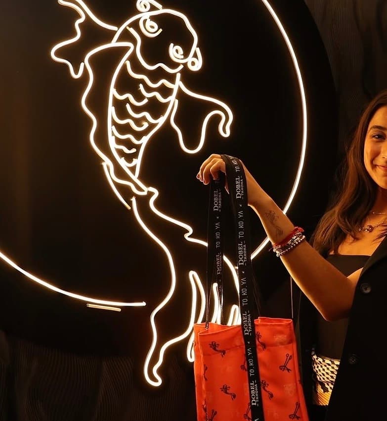Chica sonriendo y cargando una bolsa de Tokoya